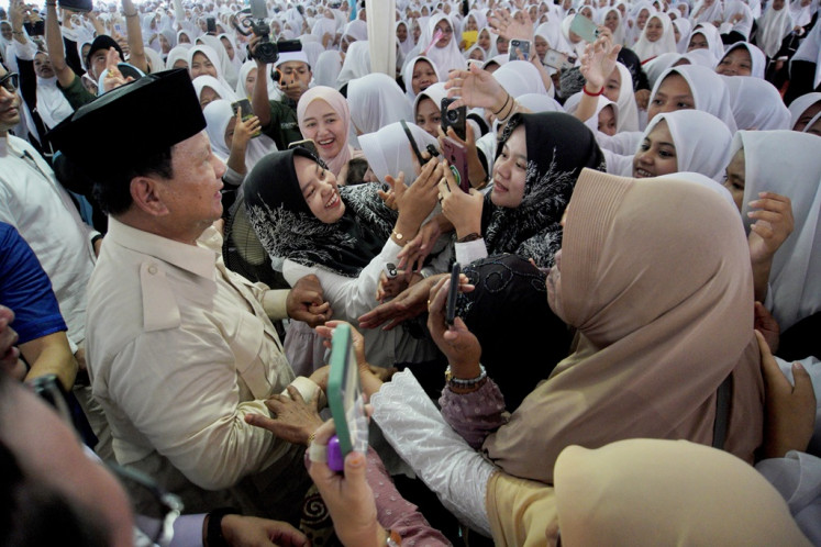 Defense Minister and presidential candidate Prabowo Subianto greets residents when visiting Zainul Hasan Genggong Islamic boarding school (pesantren) in Probolinggo, East Java on Dec. 2, 2024. 