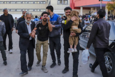 People injured in two explosions in quick succession that struck a crowd marking the anniversary of the 2020 killing of Guards general Qasem Soleimani, are helped outside a hospital in the southern Iranian city of Kerman on January 3, 2024. 