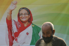 A man walks past a poster of the Awami League party featuring their leader and Bangladesh's Prime Minister Sheikh Hasina in Dhaka on January 5, 2024, ahead of Bangladesh's upcoming general election. 