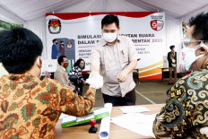 Healthy democracy: A poll worker hands plastic gloves to a voter on July 22, 2020, during a simulation for the 2020 simultaneous regional elections at the General Elections Commission (KPU) in Jakarta. During the simulation, the committee applied COVID-19 health protocols.