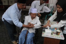 A poll station worker helps an elderly man dip his finger in ink during a 2024 election voting simulation in Malang, East Java on Dec. 27, 2023. The Malang Elections Commission (KPU) held the simulation for poll station workers and to provide public education for the general public on the 2024 general election.