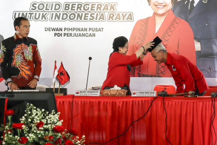 Indonesian Democratic Party of Struggle (PDI-P) Megawati Soekarnoputri (center) puts a cap on Ganjar Pranowo's (right) head while observed by President Joko “Jokowi“ Widodo following the party's announcement of the former Central Java governor's presidential bid for the 2024 presidential election in Bogor, West Java, on April 21, 2023.