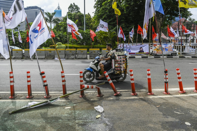 A motorist passes by election campaign banners installed by political parties ahead of the 2024 election in Menteng, Jakarta, on Jan. 8, 2024. The General Elections Commission (KPU) prohibits election candidates and political parties from installing banners and other campaign materials on public facilities.