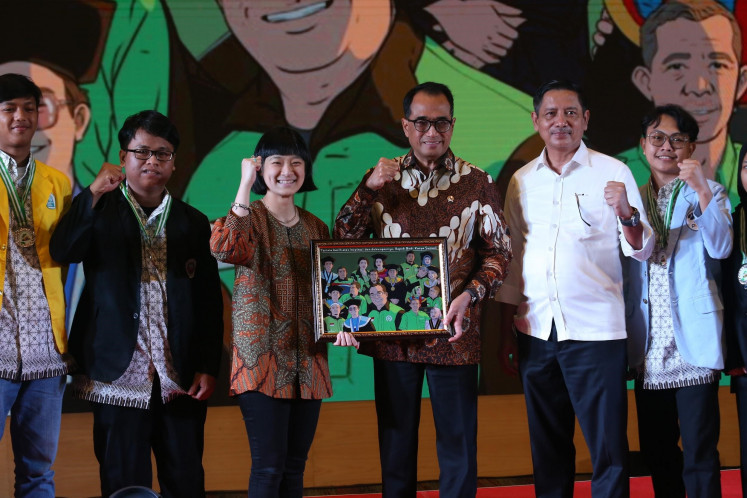 Director and president of the GoTo Group On-Demand Services Business Unit, Catherine Hindra Sutjahyo (center), alongside Gojek Scholarship graduates, hands over a memento to Transportation Minister Budi Karya Sumadi, who was accompanied by Director General of Land Transportation at the Transportation Ministry Hendro Sugiatno in an Inspirational Talk event with Budi in Jakarta on Dec. 11.
