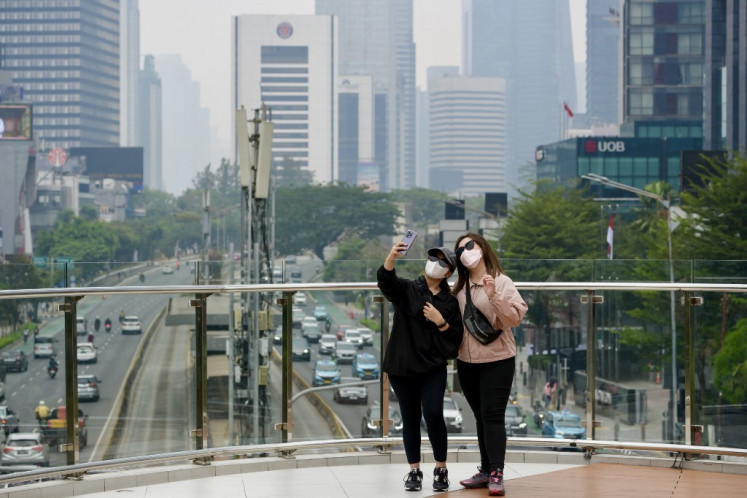 Two women take a selfie while wearing face masks in Jakarta on a polluted day on October 1, 2023. (Photo by BAY ISMOYO / AFP)