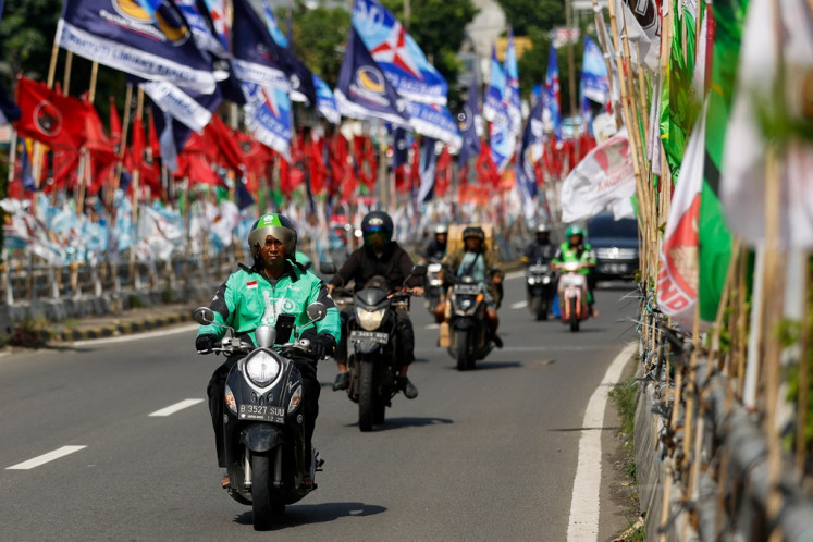 Motorists drive past the flags of various political parties along a street in Jakarta on Jan. 12, almost exactly a month ahead of the 2024 general election.