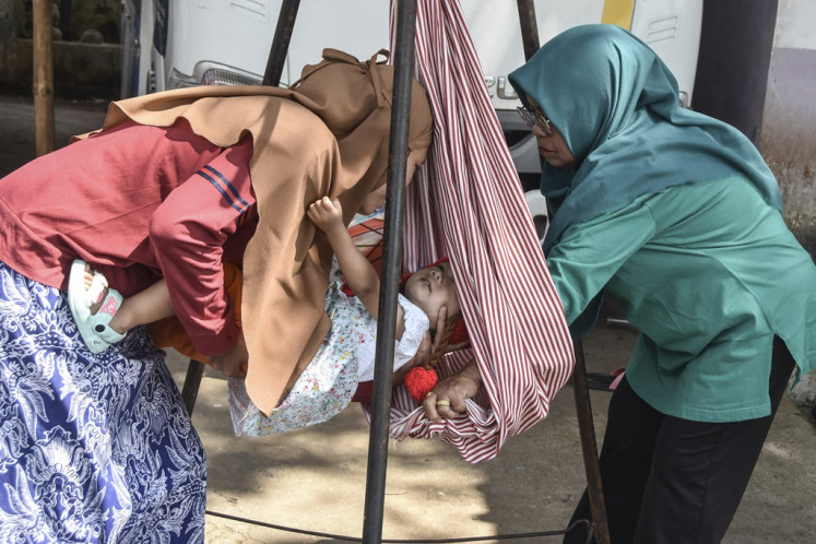 A health cadre weigh a children on a scale at an integrated health post (Posyandu) in Ciamis regency, West Java on Jan. 16, 2024. The government allocates Rp 187.5 trillion in the 2024 state budget for stunting prevention.