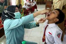 A health worker administers an oral vaccine to a student on Jan. 16, 2024, during a municipal polio immunization campaign at elementary schools in Malang, East Java.