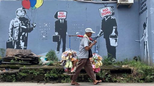 A vendor walks past a mural encouraging vigilance against the spread of fake news on Jl. KH Hasyim Ashari in Tangerang, Banten, on Feb. 22, 2021.