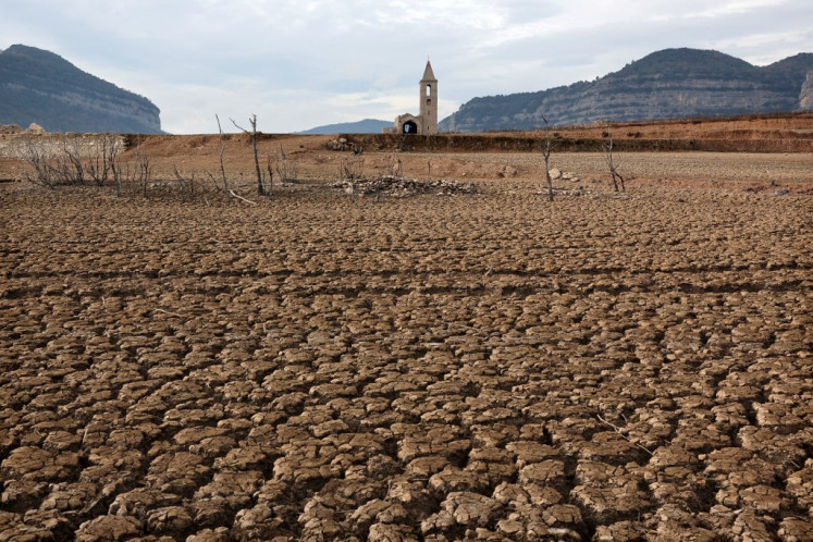This photograph taken on January 15, 2024 shows the dry soil next to the low water-level reservoir of Sau with in background Sant Roma de Sau church, in the province of Girona in Catalonia. Catalonia struggles with historic drought for three years, with some residents already experiencing water restrictions in their daily life. 