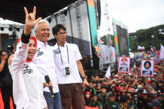 Presidential candidate Ganjar Pranowo (center) greets his supporters alongside his wife Siti Atikoh Supriyanti (left) and son Alam Ganjar (right) during a campaign event at Tegalega Square in Bandung, West Java, on Jan. 21, 2024.