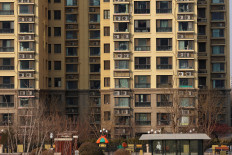 A person sits in front of residential buildings developed by China Evergrande Group, after a court ordered the liquidation of the property developer, in Beijing, Jan. 29, 2024.