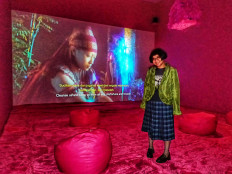 Seeking blessings: Natasha Tontey poses in front of her video art “Garden Amidst the Flame” (2022), a 27-minute video featuring a group of girls undergoing the Karai ritual from Minahasa, North Sulawesi. Karai is an ancient Minahasan ritual to seek blessings from the ancestors.