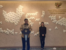 Coordinating Economic Minister Airlangga Hartarto (left) and a sign language interpreter (right) stand before the press in his office in Jakarta on Feb. 5, 2023.