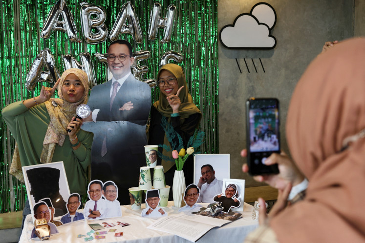 Women pose for a photograph with a cutout depicting presidential candidate Anies Baswedan during the Humanies Cup Sleeve event at the Kopi Nako cafe in Jakarta, on Feb. 4, 2024.