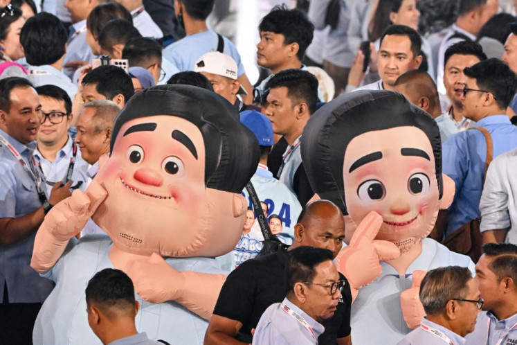 People walk past mascots depicting presidential candidate and Defence Minister Prabowo Subianto (left) and vice presidential candidate Gibran Rakabuming Raka during their election campaign event at the Indonesia Arena in Jakarta on February 5, 2024. 
