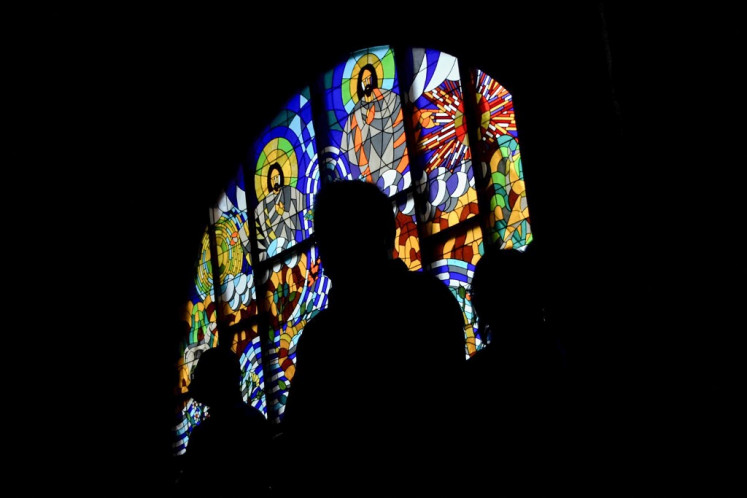 Churchgoers are silhouetted as they attend Christmas mass in Bekasi on December 25, 2021.