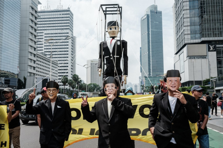 Participants wearing printed face masks of the three presidential candidates Anies Baswedan (left), Prabowo Subianto (center) and Ganjar Pranowo (right) walk in front of a giant puppet depiction of Pinocchio during a demonstration organised by various humanitarian and environmental organisations and students, calling for the right choice to recover from the destruction of democracy, human rights and climate change, ahead of the upcoming February 14 presidential election in Jakarta on February 7, 2024. 