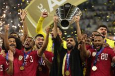 Qatar's forward #10 Hassan Al-Haydos lifts the Qatar 2023 AFC Asian Cup trophy as his team celebrates during the podium ceremony after the final football match between Jordan and Qatar at the Lusail Stadium in Lusail, north of Doha on February 10, 2024. 