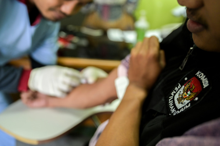 A community health center (Puskesmas) worker administers multivitamins to a General Elections Commission (KPU) official at Pramuka Island in Thousand Islands regency, Jakarta on Feb. 11, 2024. Health authorities are gearing up by checking the health condition of election officials and poll administrators ahead of the 2024 general election on Feb. 14.