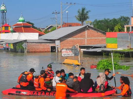 Volunteers evacuate residents on a flooded highway in Karanganyar district, Demak regency, Central Java, on Feb. 9, 2024. The flood was caused by breaches in embankments on the Wulan River and Jratun River.