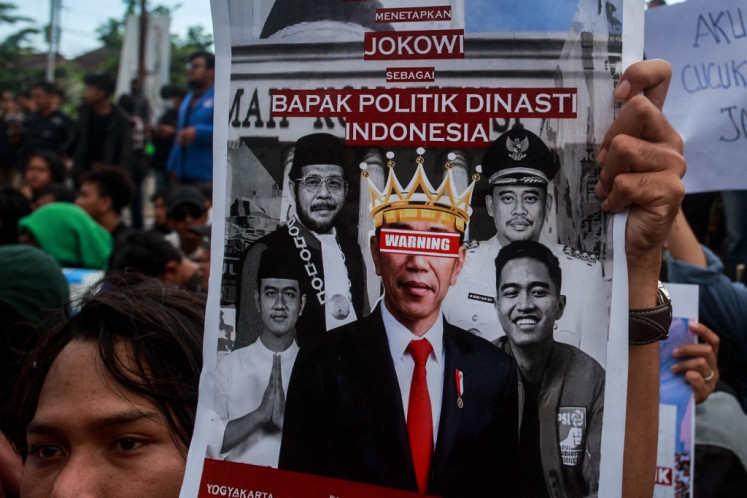 A student holds a poster showing President Joko “Jokowi“ Widodo and his family members as hundreds of students protest against his family's political dynasty in the 2024 elections in Yogyakarta on February 12, 2024. 