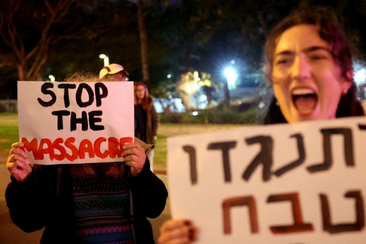 Demonstrators gather with signs during a protest by Israeli left-wing activists against the war in the Gaza Strip and the planned ground operation in Rafah, outside the Kirya military base which houses the Defense Ministry in Tel Aviv on February 13, 2024, amid the ongoing conflict in Gaza. 