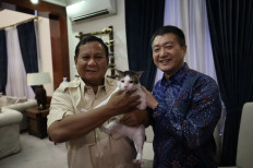 Defense Minister Prabowo Subianto (left) and Chinese Ambassador to Indonesia Lu Gang (right) take a picture with the former's pet Bobby at a private event in South Jakarta on Feb. 18, 2024.