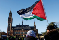 Protesters hold a Palestinian flag as they gather outside the International Court of Justice (ICJ) as judges rule on emergency measures against Israel following accusations by South Africa that the Israeli military operation in Gaza is a state-led genocide, in The Hague on Jan. 26, 2024.
