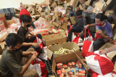 Workers package food in bags labeled as donations from President Joko “Jokowi” Widodo.