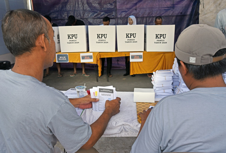 Poll workers prepare ballot papers during a revote at a polling station in Serang, Banten on Feb 21, 2024. The General Elections Commission (KPU) holds revote in four polling stations in the city after officials find underage voters, double voting and voters without proper documentation.