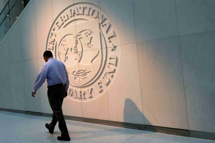 A man walks on May 10, 2018, past the International Monetary Fund (IMF) logo at its headquarters in Washington, the United States.