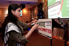 Activist Natalia Latif tapes a Vote Uncommitted sign on the speaker's podium during an uncommitted vote election night gathering as Democrats and Republicans hold their Michigan primary presidential election, in Dearborn, Michigan, .S, February 27, 2024.