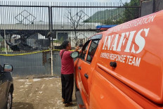 A member of the Bandar Lampung City Police' Indonesian Automatic Fingerprint Identification System (Inafis) team takes a picture of a burned warehouse in Bandar Lampung on Wednesday, Feb. 29, 2024. The warehouse stored used oil and the police suspected it was also used to hoard diesel fuel after the warehouse caught fire on Feb. 28, 2024.