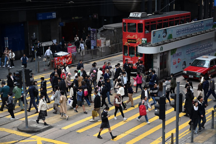 People cross an intersection in the central business district of Hong Kong, China, on Feb. 27, 2024.