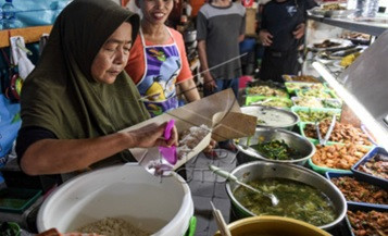 A food vendor serves customers in Jakarta on Feb. 22, 2024, at her &lsquo;warteg&rsquo;, a food stall specializing in the cuisine of Tegal, Central Java.