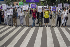 Participants in an International Women’s Day march hold placards on March 8, 2024, along a pedestrian crossing in Bandung, West Java.