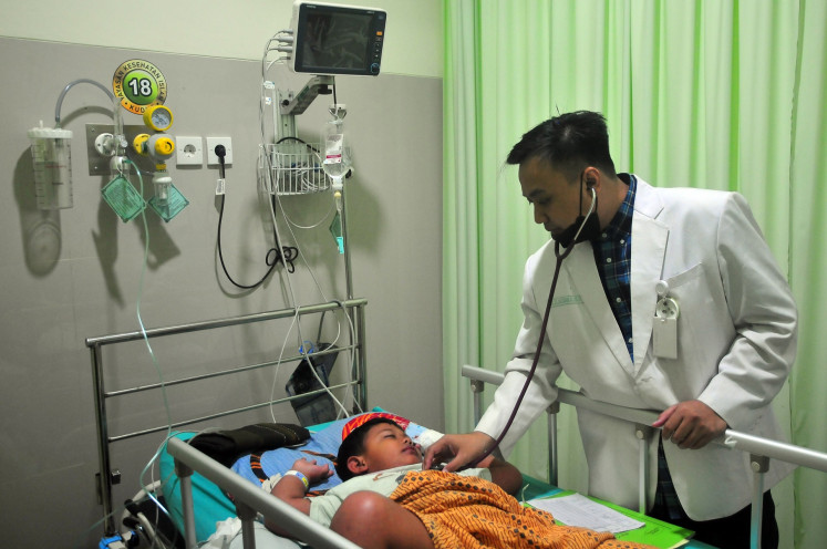 A doctor examines a dengue fever patient on March 8, 2024 at Sunan Kudus Islamic Hospital in Kudus, Central Java.