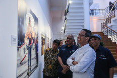 Acting Jakarta goernor Heru Budi Hartono (second right) looks at a photo in the Pers Demo-Krasi dan Pembangunan photo exhibition at the Antara Heritage Center Complex Gallery in Jakarta on Feb. 16, 2024 with state news agency Antara president director Akhmad Munir (second right) and exhibition curator Ismar Patrizki (right).