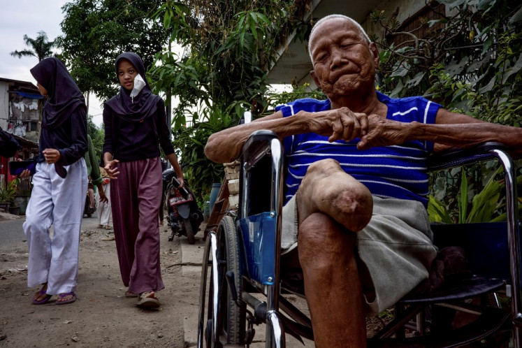 Former leprosy patient Harto sits in a wheelchair on Jan. 18, 2023, in front of his house in ‘kampung kusta’ (leprosy village) in Tangerang, Banteng. Residents of the densely populated neighborhood just outside of Jakarta are fighting to reclaim their dignity and future after battling for decades against the stigma and discrimination of leprosy, a curable but often neglected disease.