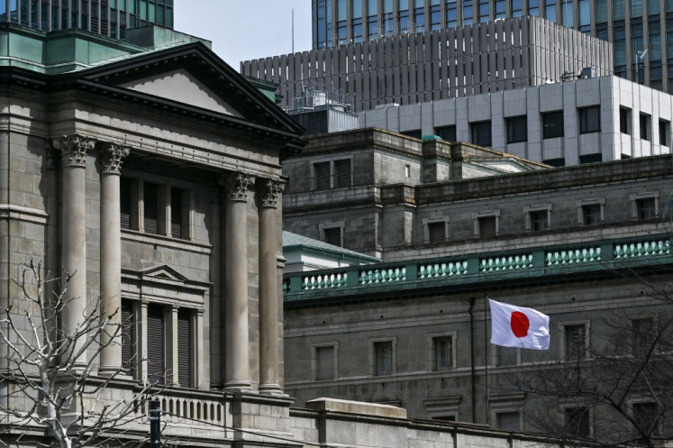 The Japanese flag flies over part of the Bank of Japan (BoJ) headquarters in central Tokyo on March 19, 2024.