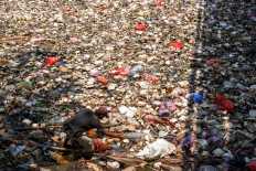 A scavenger searches for items among the floating garbage in the Cibanten River in Serang, Banten on September 20, 2023.