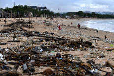 Trash collectors remove plastic and other debris washed ashore at Kedonganan Beach, Badung regency, in Bali on April 12, 2023. 