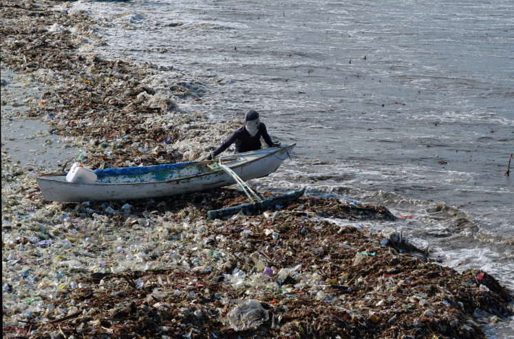 Plastic 'paradise': A fisherman pulls his boat out to sea on March 20, 2024, across waste that covers much of Kedonganan Beach in Badung, Bali. Kedonganan is one of Bali’s beaches most polluted with plastic materials.