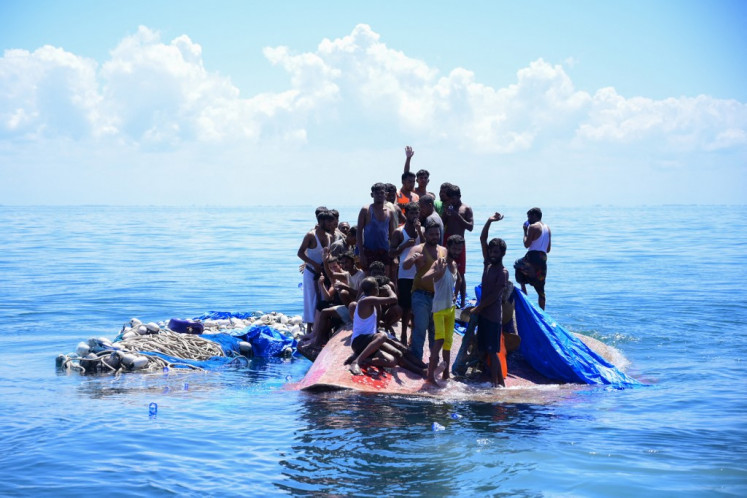 Rohingya refugees wait to be rescued from the hull of their capsized boat as a National Search and Rescue Agency (BASARNAS) vessel approaches in waters some 29 kilometers off west Aceh on March 21, 2024.