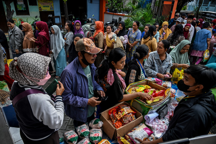 People queue in line to buy basic daily necessities at a cheap market event held by the government in Surabaya to maintain stable food supplies and prices on March 12, 2024.