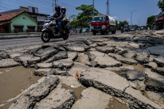 Motorists drive on March 24, 2024, along a flood-
damaged portion of the Demak-Kudus highway in
Karanganyar district, Demak regency, Central Java.