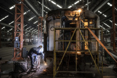 Workers perform maintenance on a train car on March 26, 2024, at the Manggarai train depot in Jakarta. State-owned railway company Kereta Api Indonesia (KAI) is preparing 1,664 regular trains plus 366 additional trains to run from March 31 to April 21 for the Idul Fitri exodus season this year. 