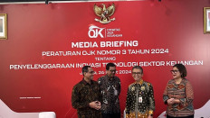 Hasan Fawzi (left), executive head of financial technology innovation, digital financial assets and crypto supervision at the Financial Services Authority (OJK), smiles on Mar. 26. 2024, during a press briefing in Jakarta.