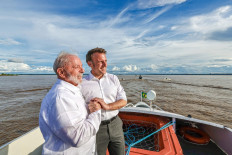 Handout picture released by the Brazilian Presidency showing Brazilian President Luiz Inacio Lula da Silva (left) and French President Emmanuel Macron holding hands as they hold a bilateral meeting while sailing at  Guajara Bay off Belem, state of Para, 